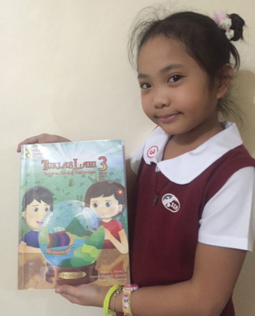 Angelica Faith Villafranca with her new Elementary Grade 3 social studies and history textbook Tuklas Lahi 3.