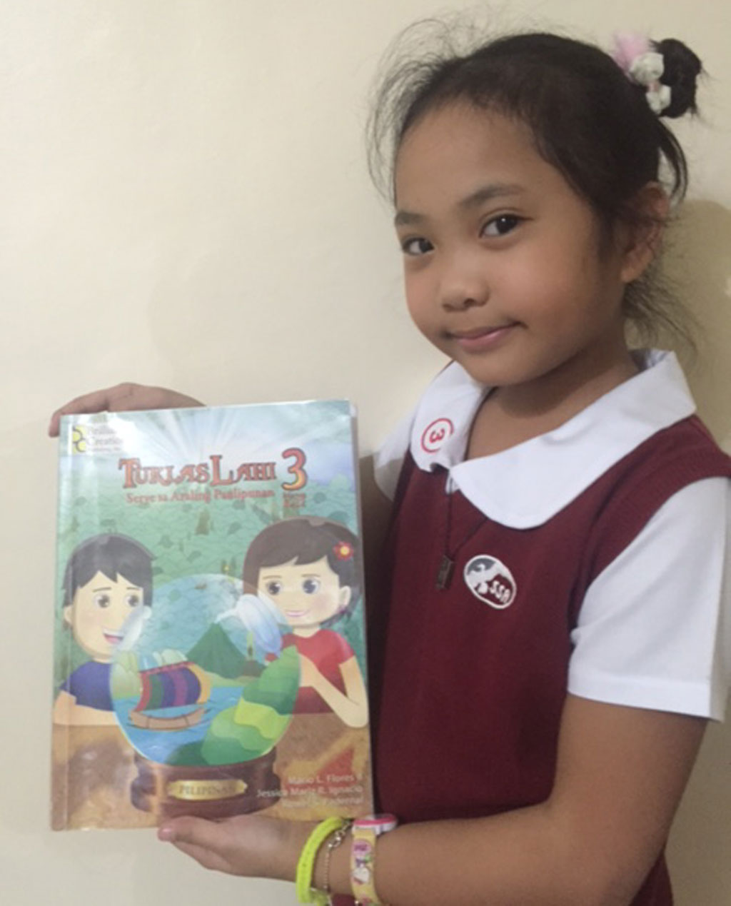 Angelica Faith Villafranca with her new Elementary Grade 3 social studies and history textbook Tuklas Lahi 3. 